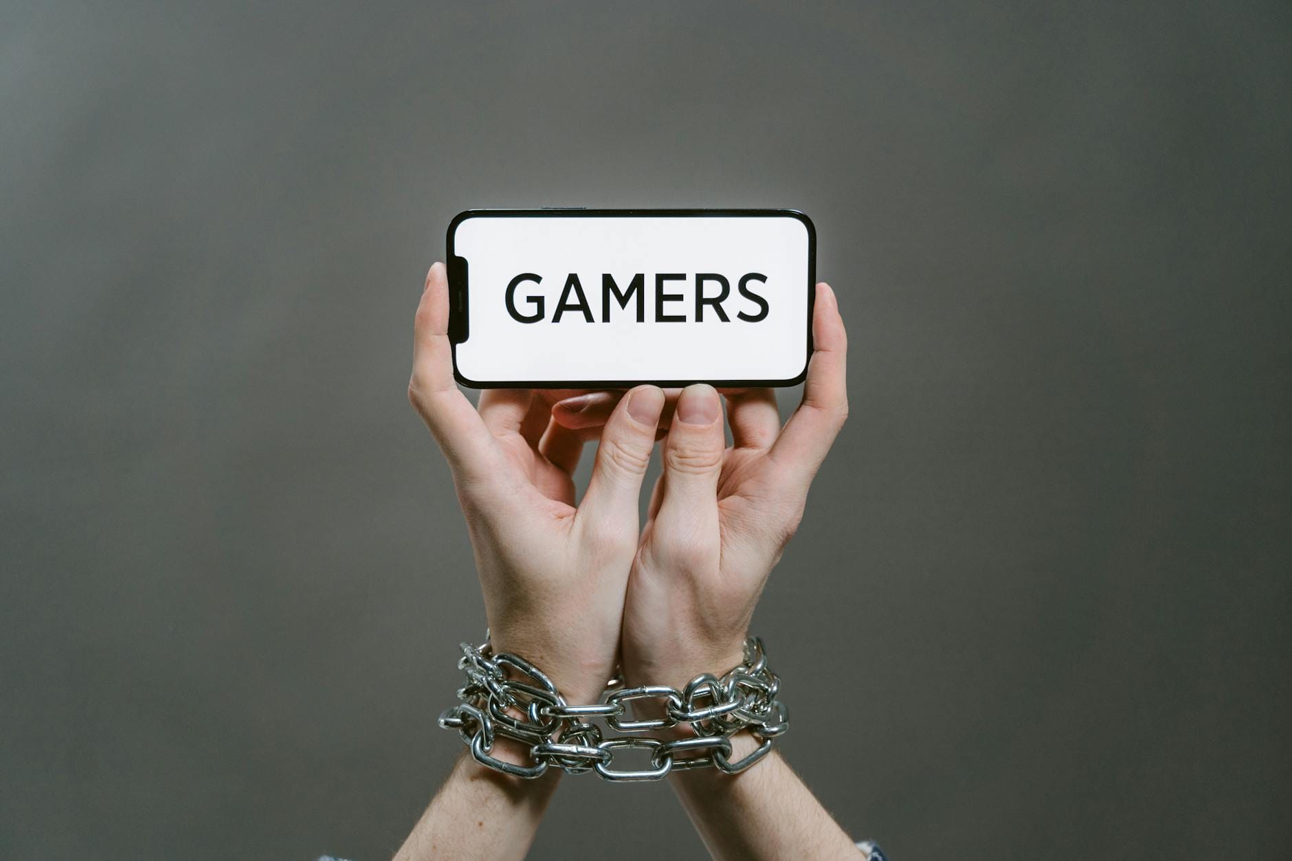 Skrępowane dłonie gracza trzymającego telefon z napisem GAMERS