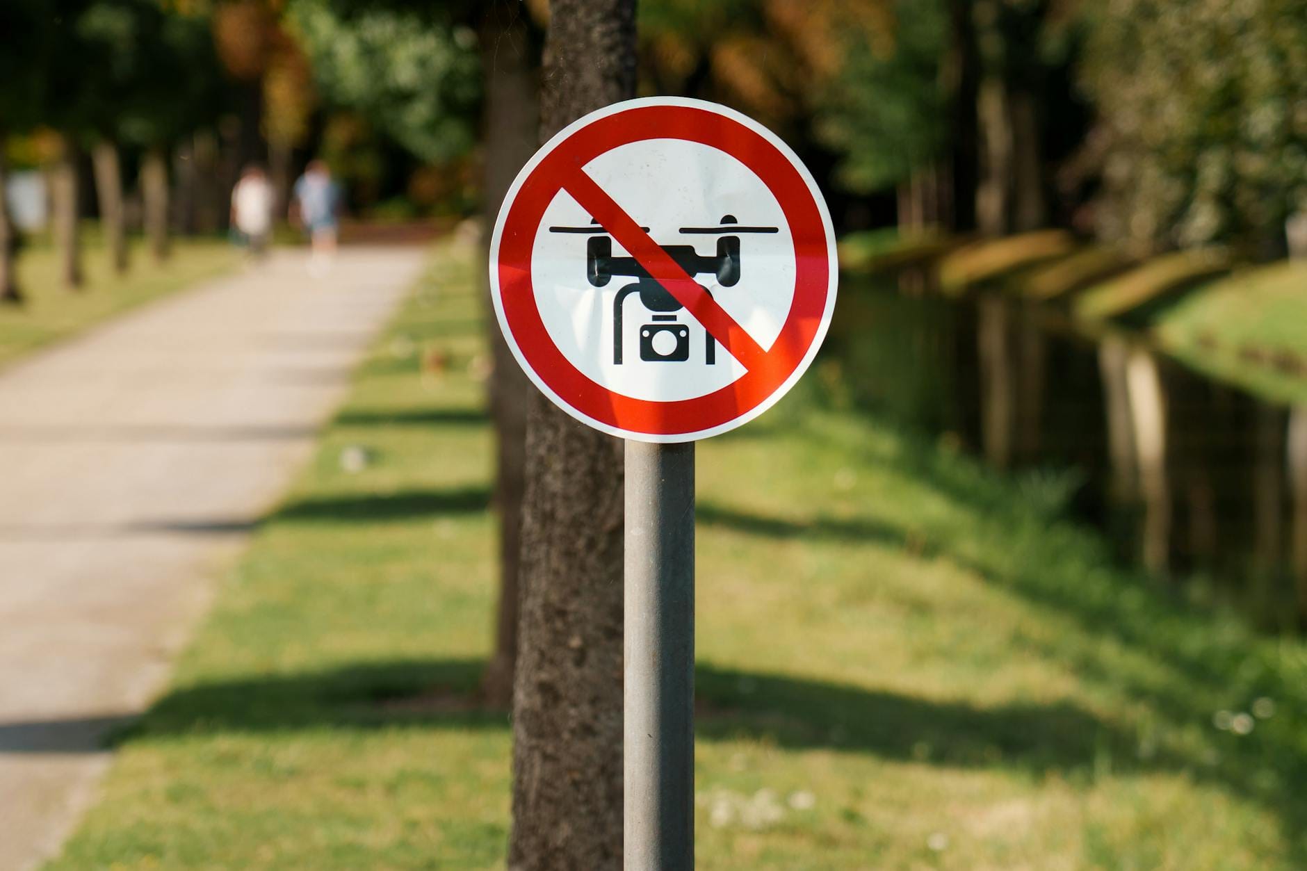 Znak zakazu dronów przy alejce w zielonym parku