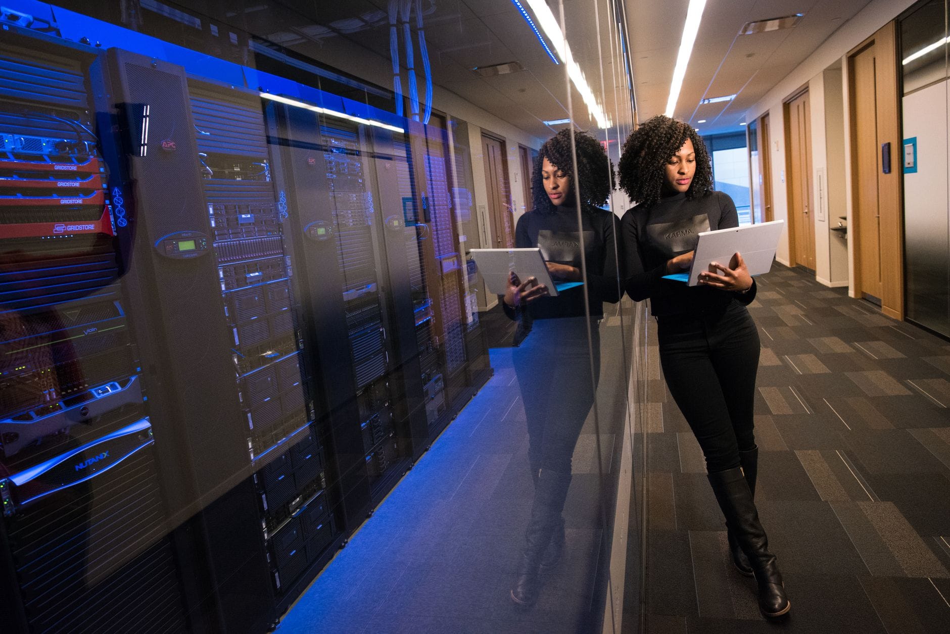 Administrator przy laptopie przechadza się między serwerami w data center